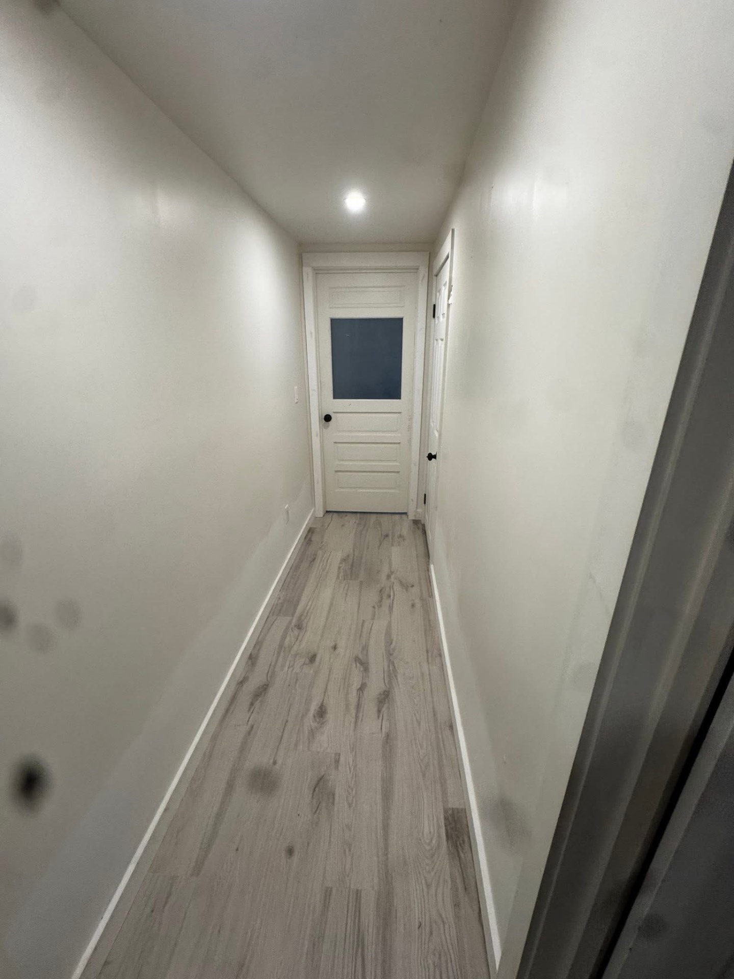 Freshly finished hallway with new gray vinyl plank flooring and trim