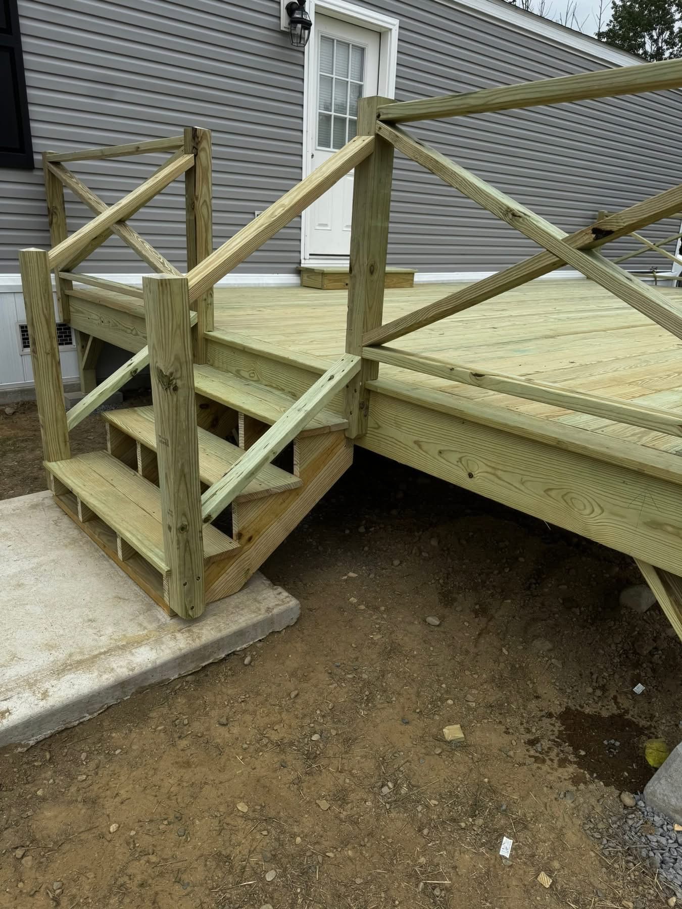 Finished pressure-treated back porch with X-brace railings and stairs