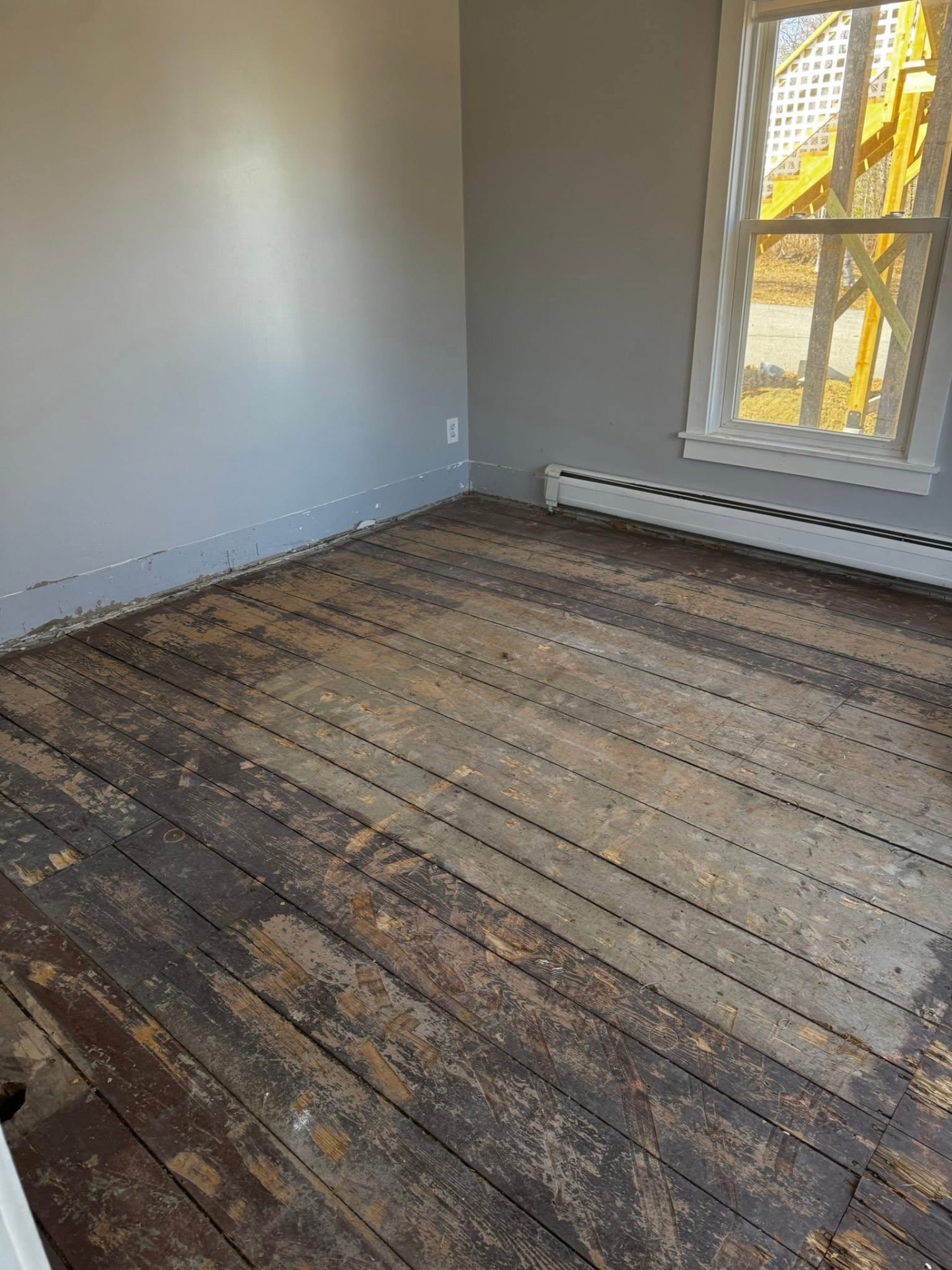 Bedroom with old damaged wood plank subfloor exposed