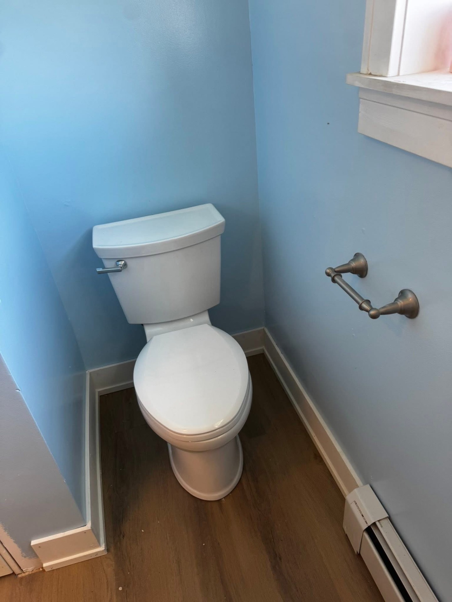 Refreshed bathroom with soft blue paint and new vinyl plank floor