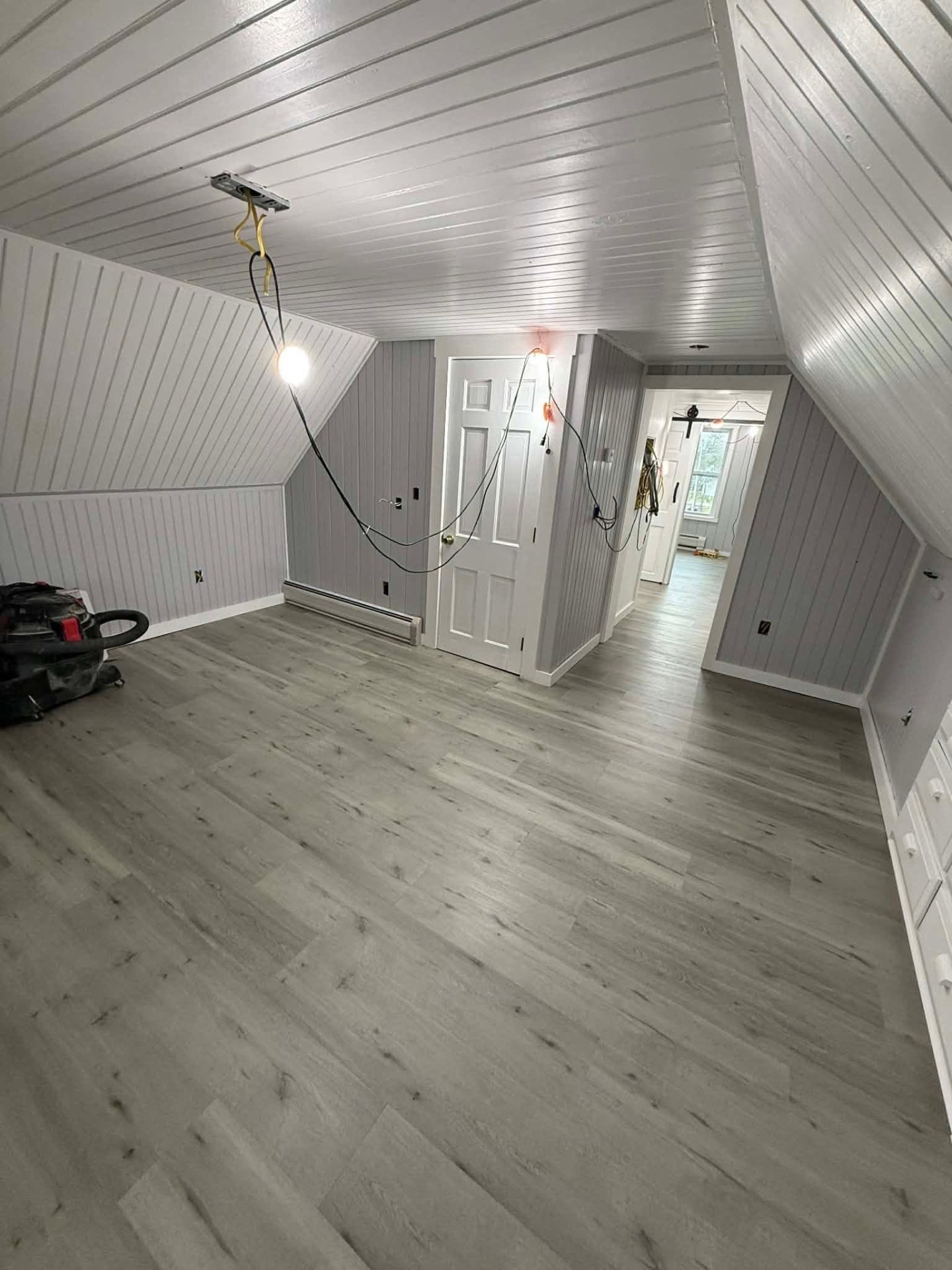 Finished attic living space with painted paneling and vinyl plank floor