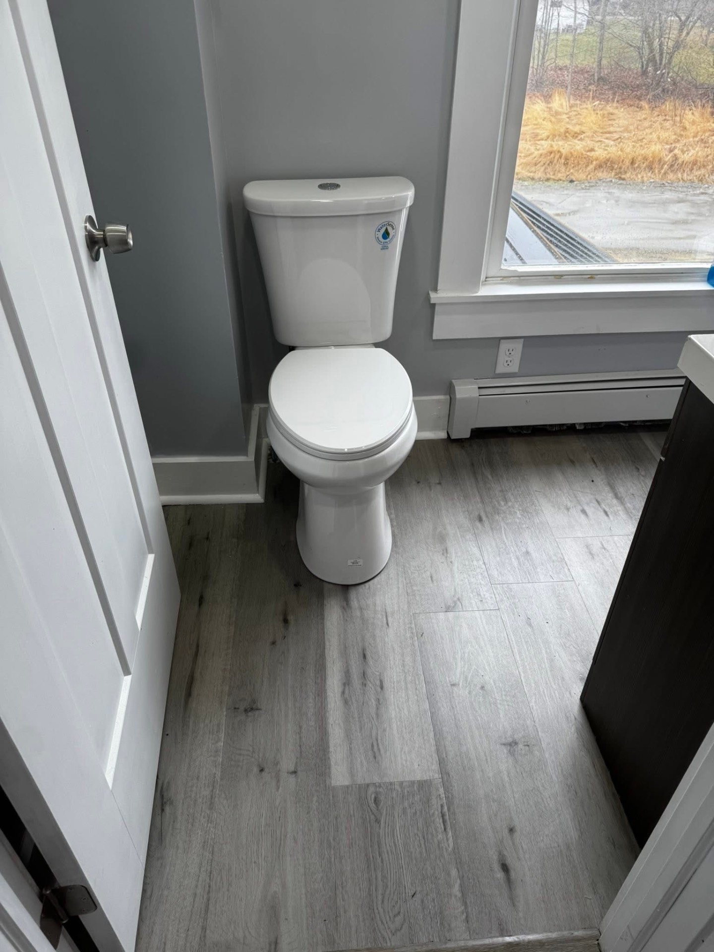 Finished half bath with new toilet, trim, and vinyl plank floor