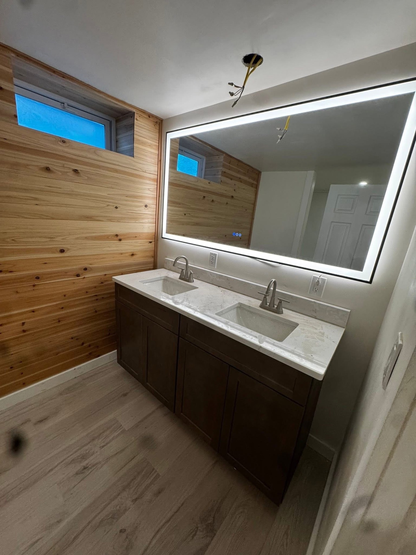 Custom bathroom with double vanity, LED mirror, and cedar accent wall
