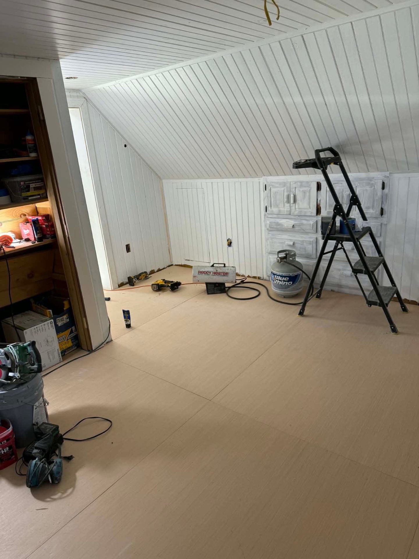 Unfinished attic room with subfloor and tools during remodel