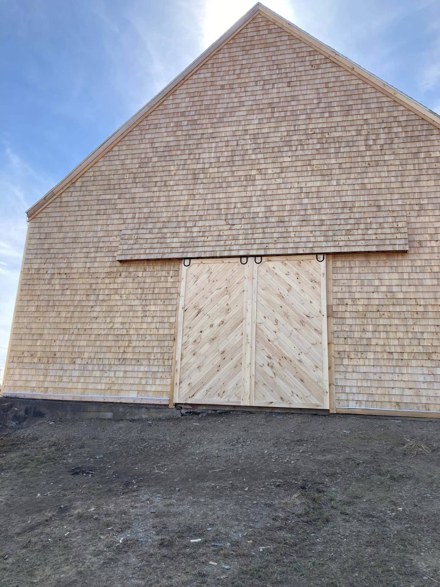 Finished cedar-shingled barn gable with custom chevron sliding doors